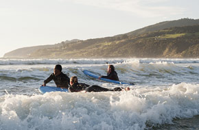 Young people taking a surfing lesson.